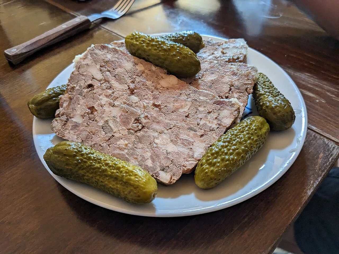Part de terrine de campagne et cornichons dans une assiette (photo d'illustration)